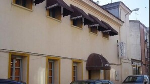 A building with multiple windows and awnings labeled "MAIRIACTIONES". There are parked cars in front of the building. - Hostal Emilio (Madrid)