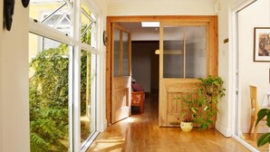 Un couloir doté d’un plancher en bois, une porte coulissante donnant sur une pièce et une plante en pot.