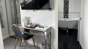 A room with a desk, chair, television, and a bathroom with a bathtub and tiled walls. - Solway Lodge Hotel (Gretna)