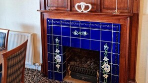 A fireplace with blue tiles and decorative items, a wooden mantel, and a patterned carpet. - Solway Lodge Hotel (Gretna)