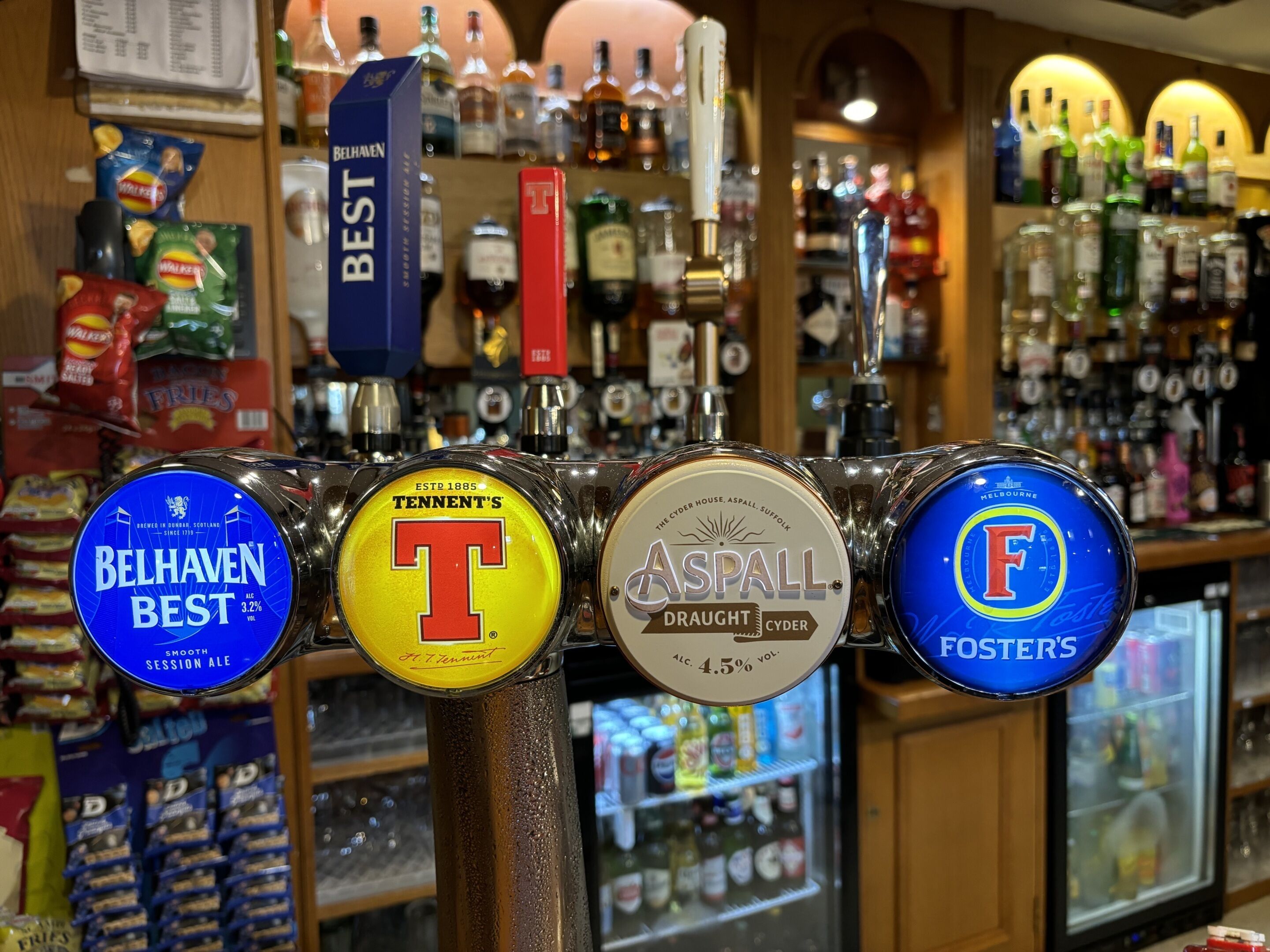Un bar con varias griferías de cerveza, incluyendo marcas como Belhaven Best, Tennents, Aspall y Foster's.