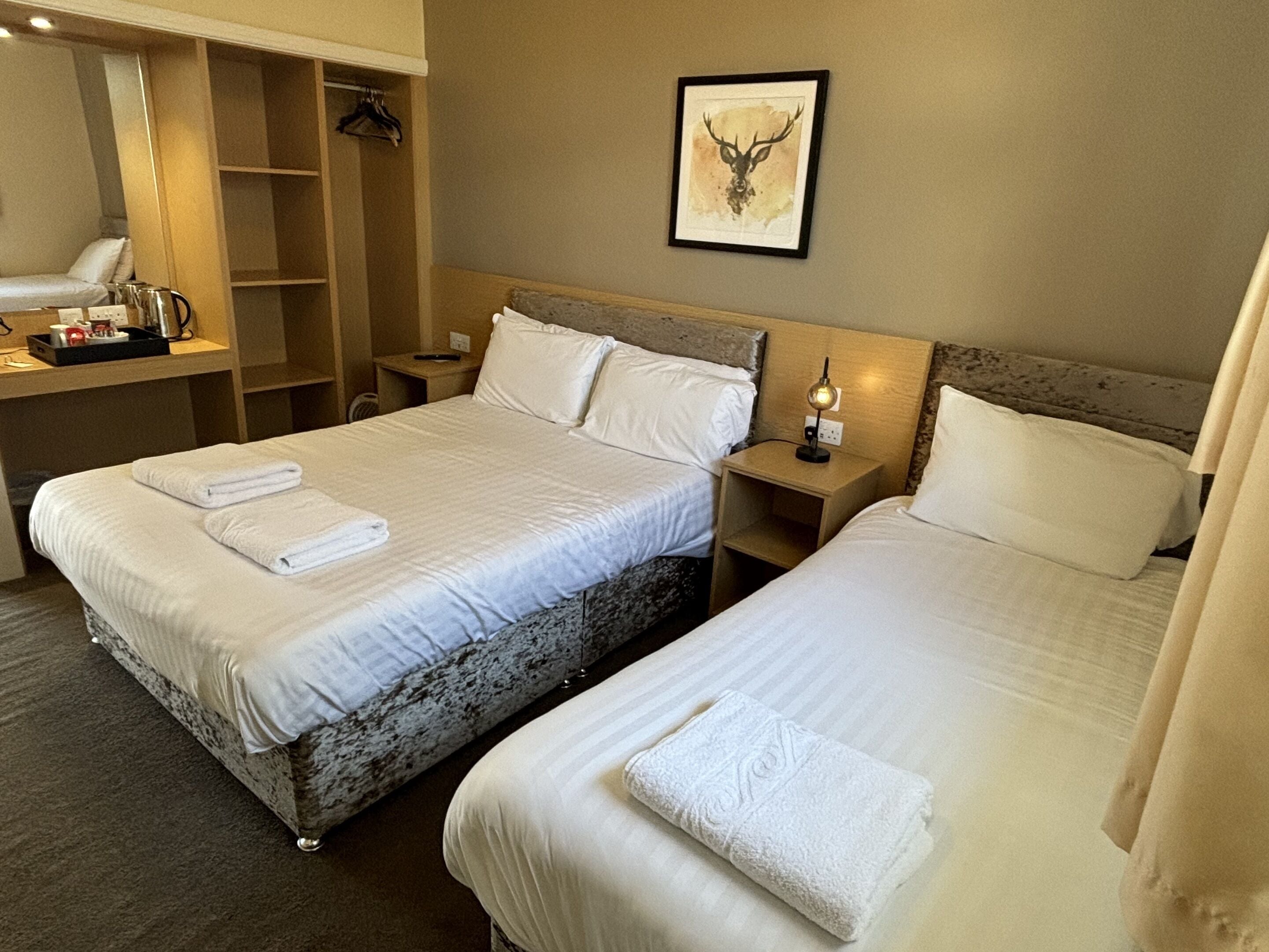 A hotel room with two beds, a desk, and a wardrobe.