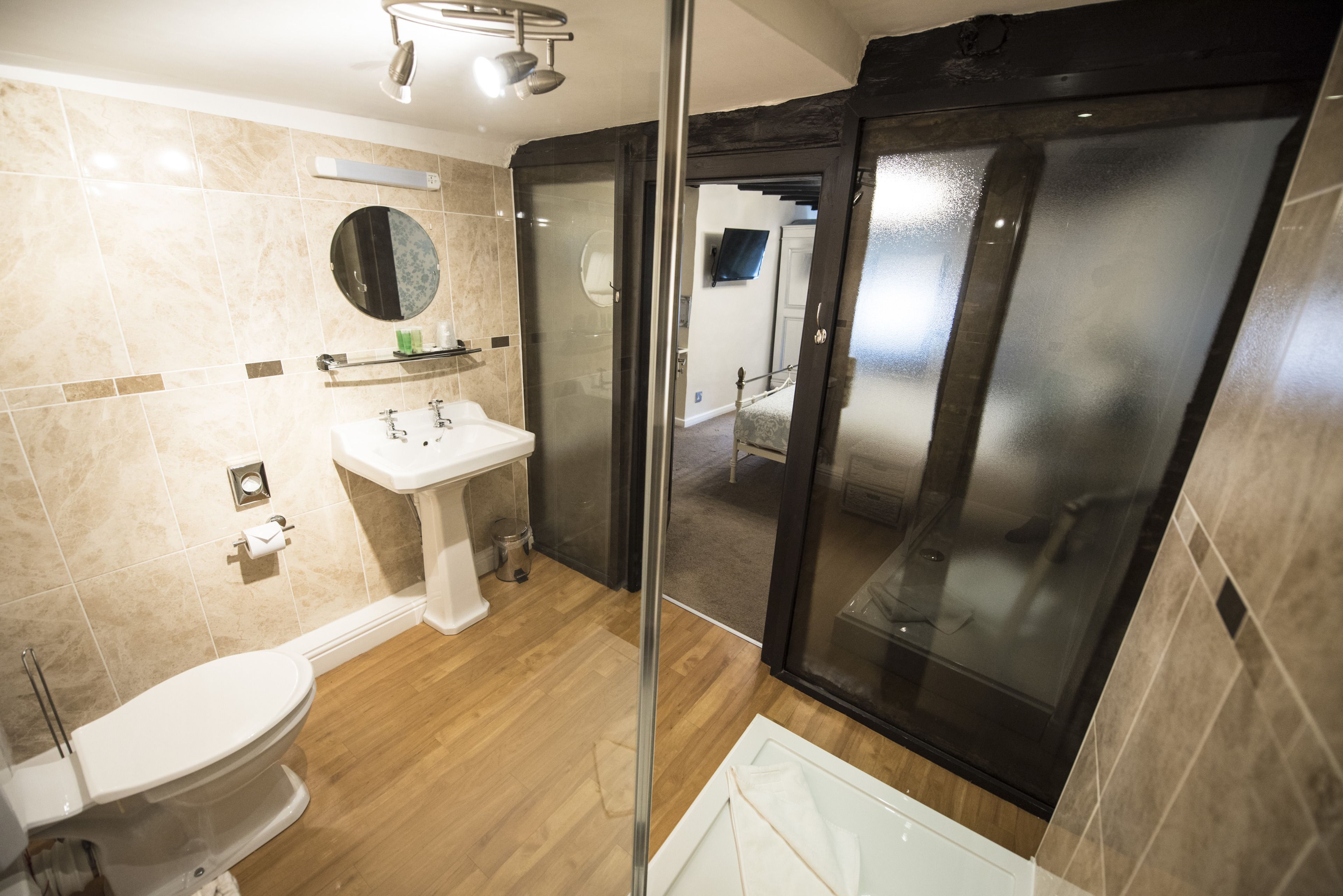 Un baño moderno con inodoro, lavabo y ducha con mampara de vidrio.