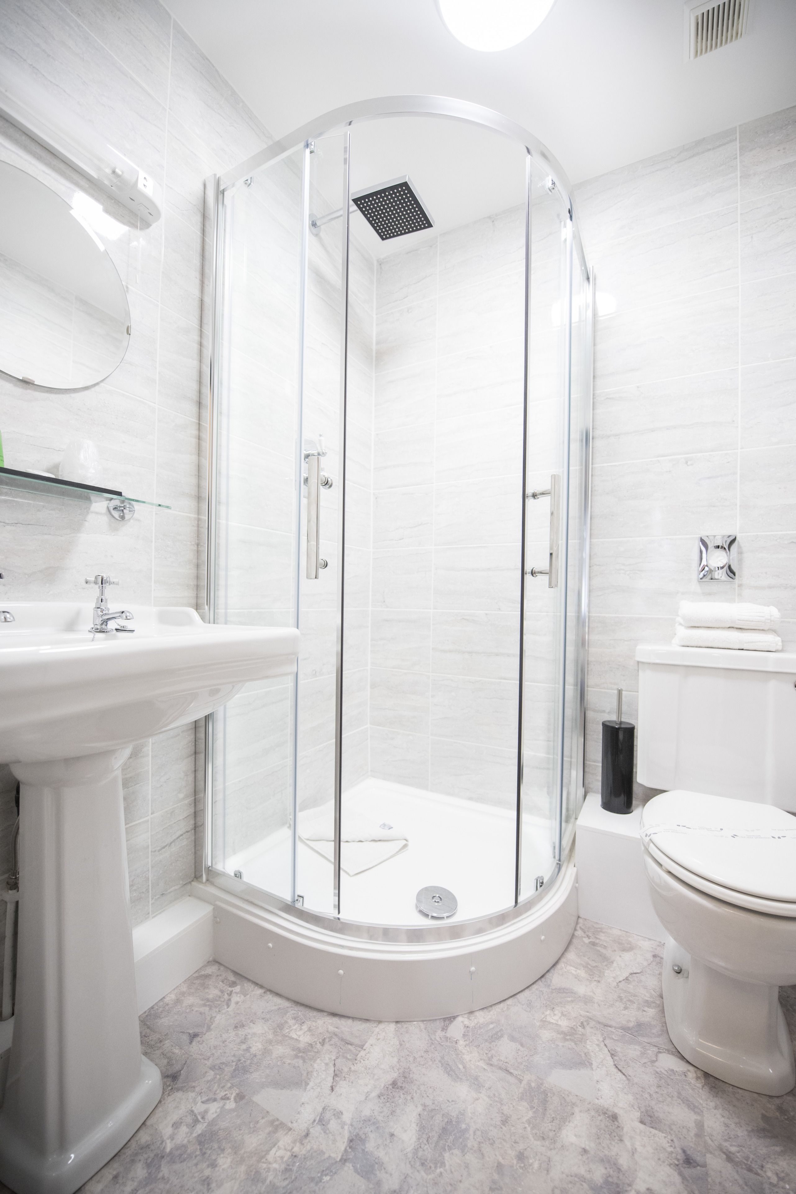 Ein modernes Badezimmer mit einer gläsernen Duschkabine, einem Standwaschbecken und einer Toilette.