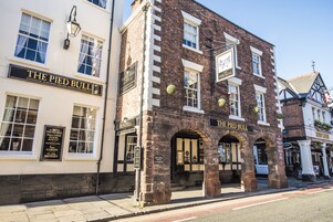 El Pied Bull, un pub tradicional con fachada de ladrillo, ventanas amplias y un cartel que anuncia su jardín de cerveza y cervecería en el lugar.