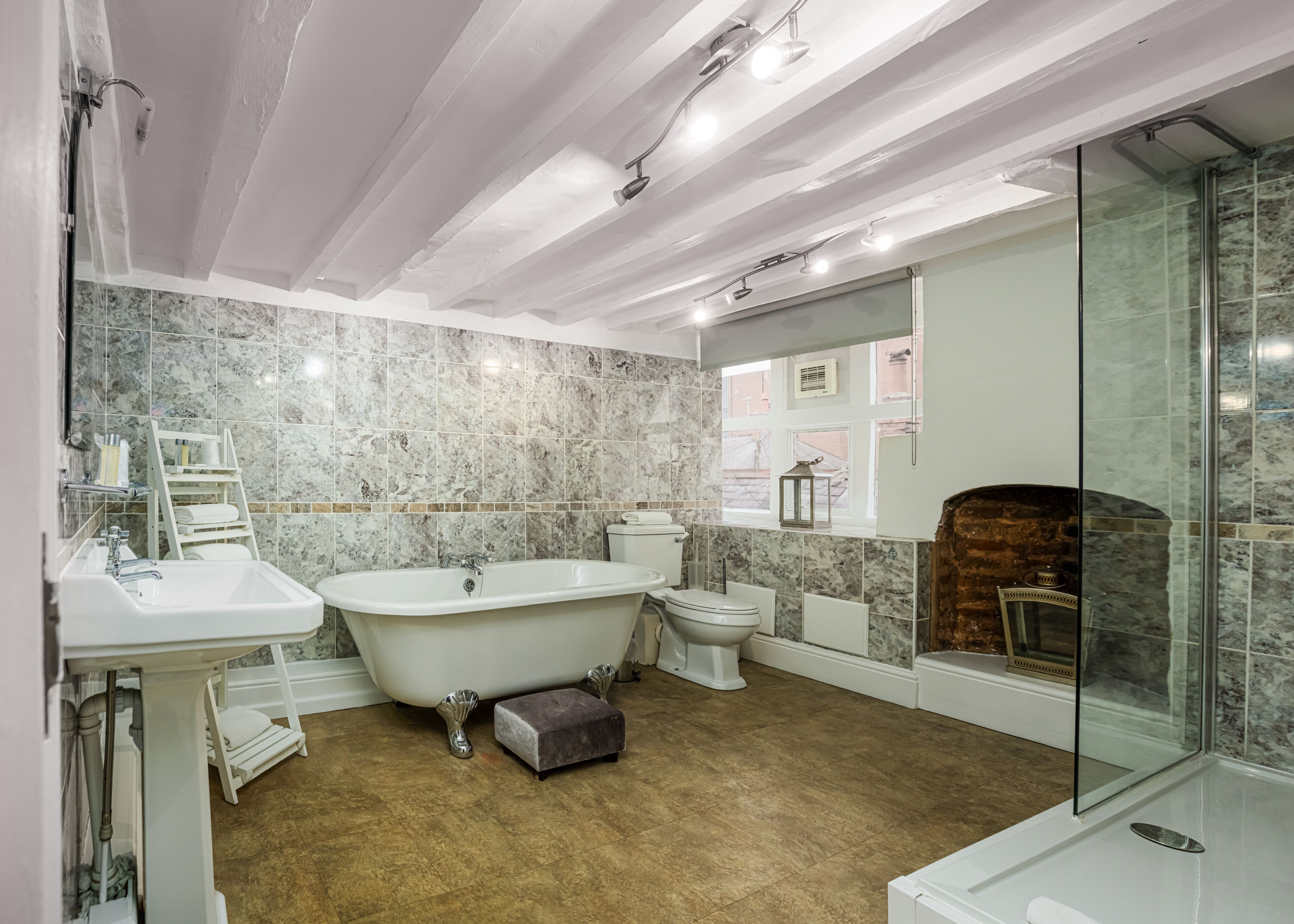 Une salle de bain comprenant une baignoire sur pieds, des toilettes, un lavabo et une douche séparée par des parois en verre.