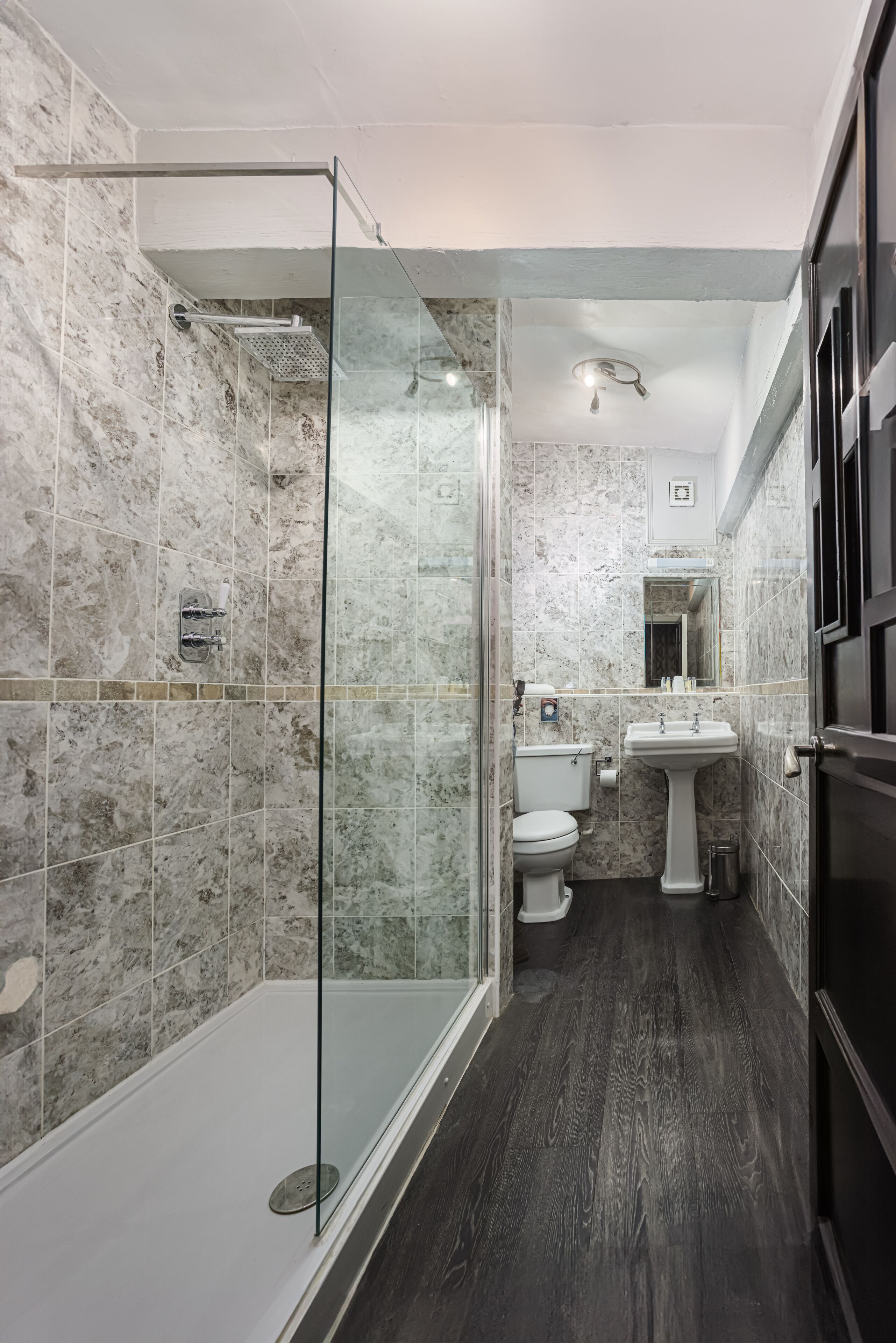 Une salle de bain avec une douche à parois de verre, des toilettes et un lavabo.