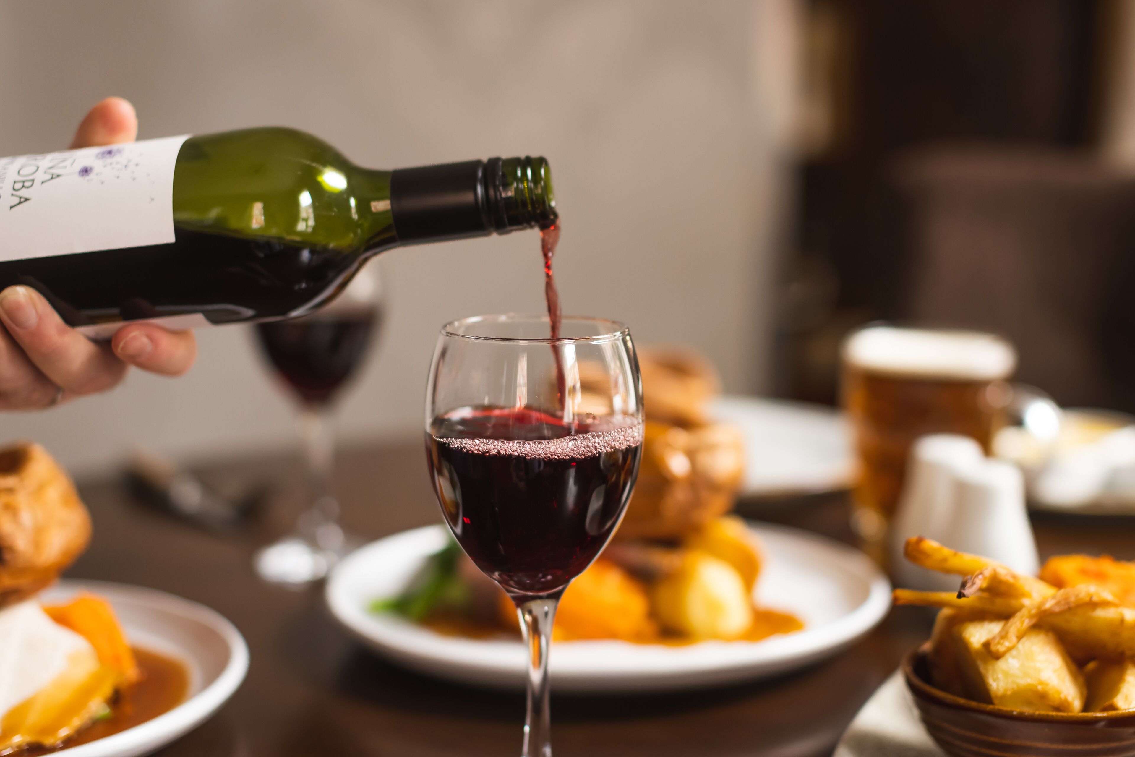 A bottle of wine being poured into a glass.