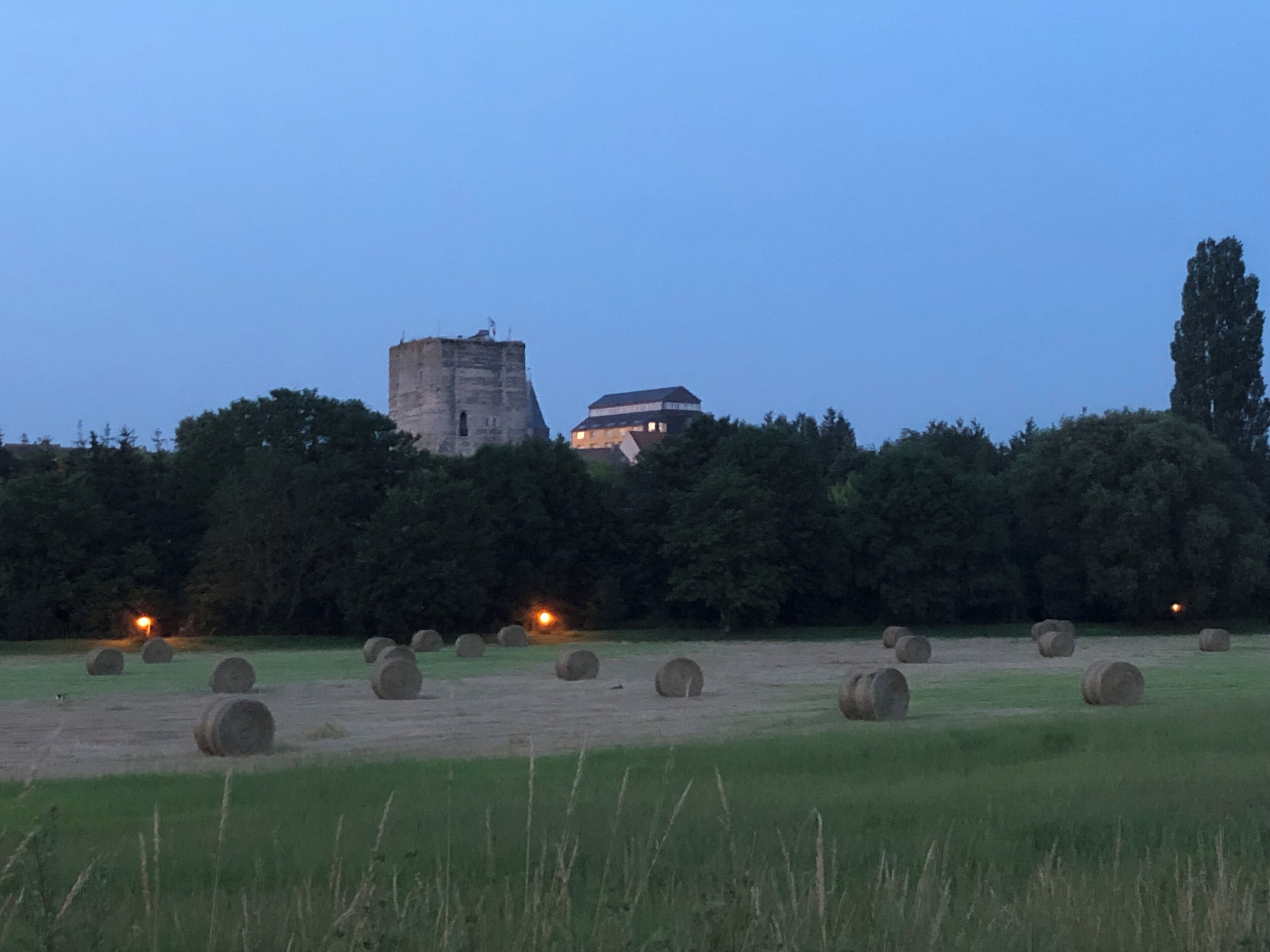 A field with hay bales and a castle in the background.