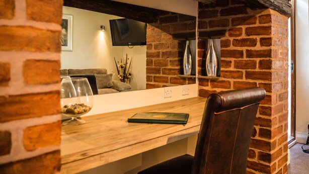 Uma sala de jantar com parede de tijolos, mesa de madeira e cadeira de couro.