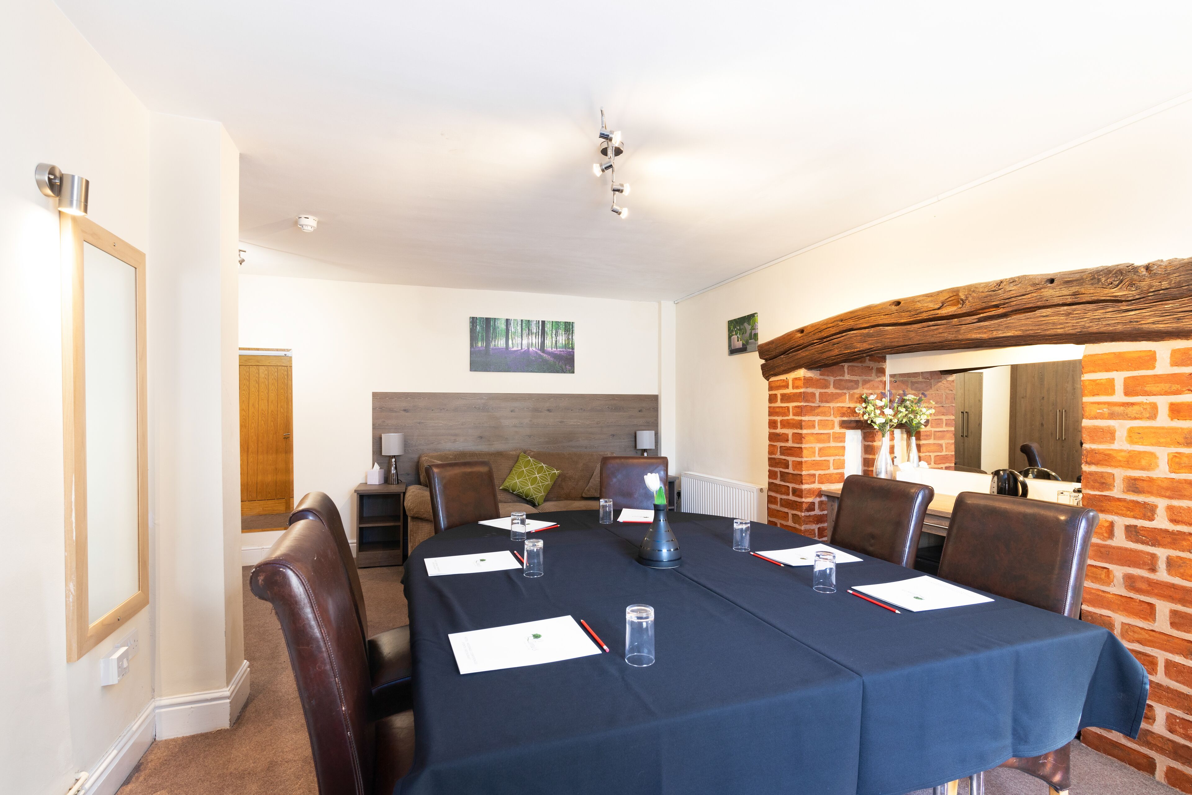 A conference room with a long table, chairs, and a brick wall.