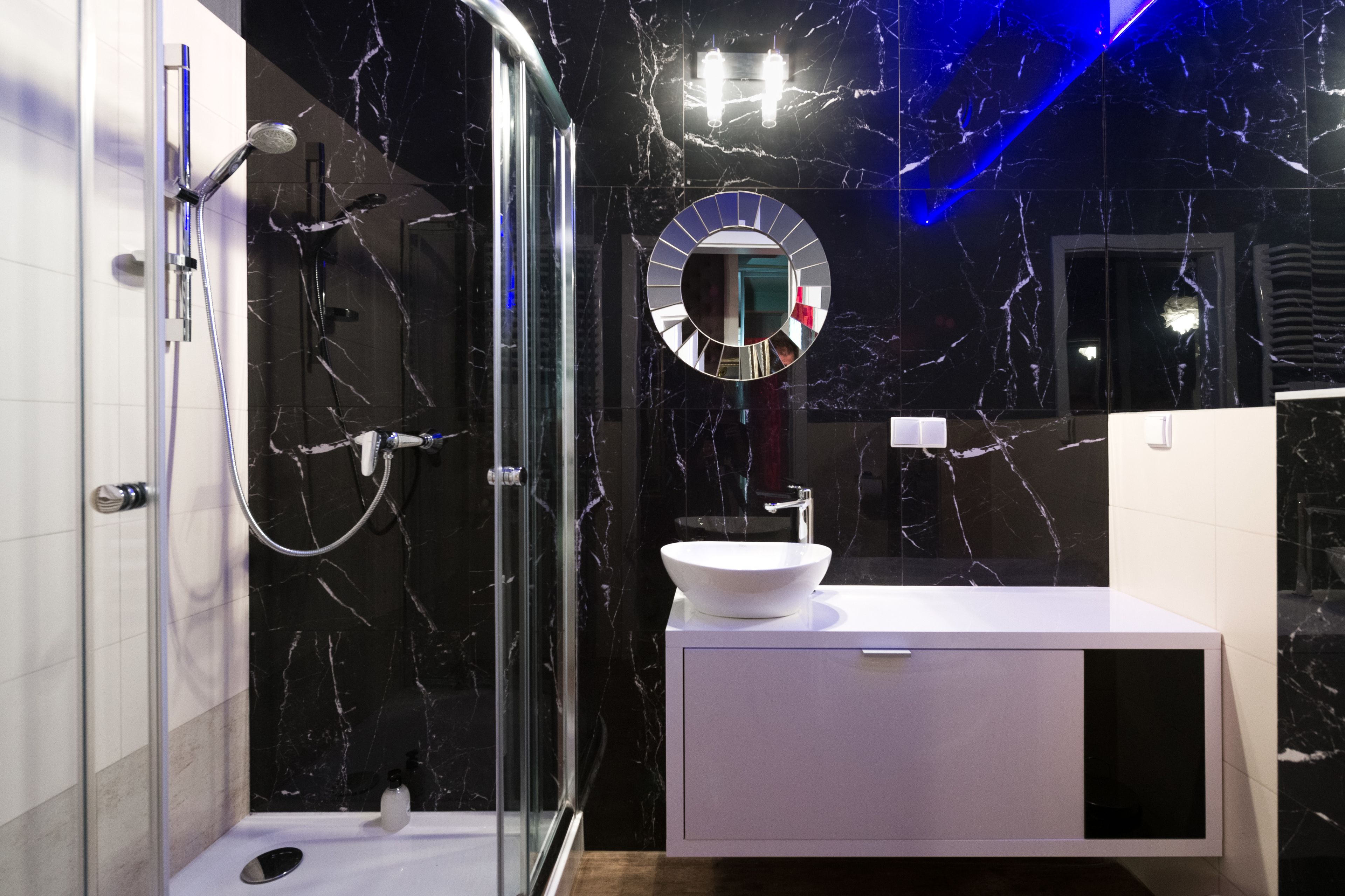 A modern bathroom with a glass-enclosed shower, a white sink, and a marble backsplash.