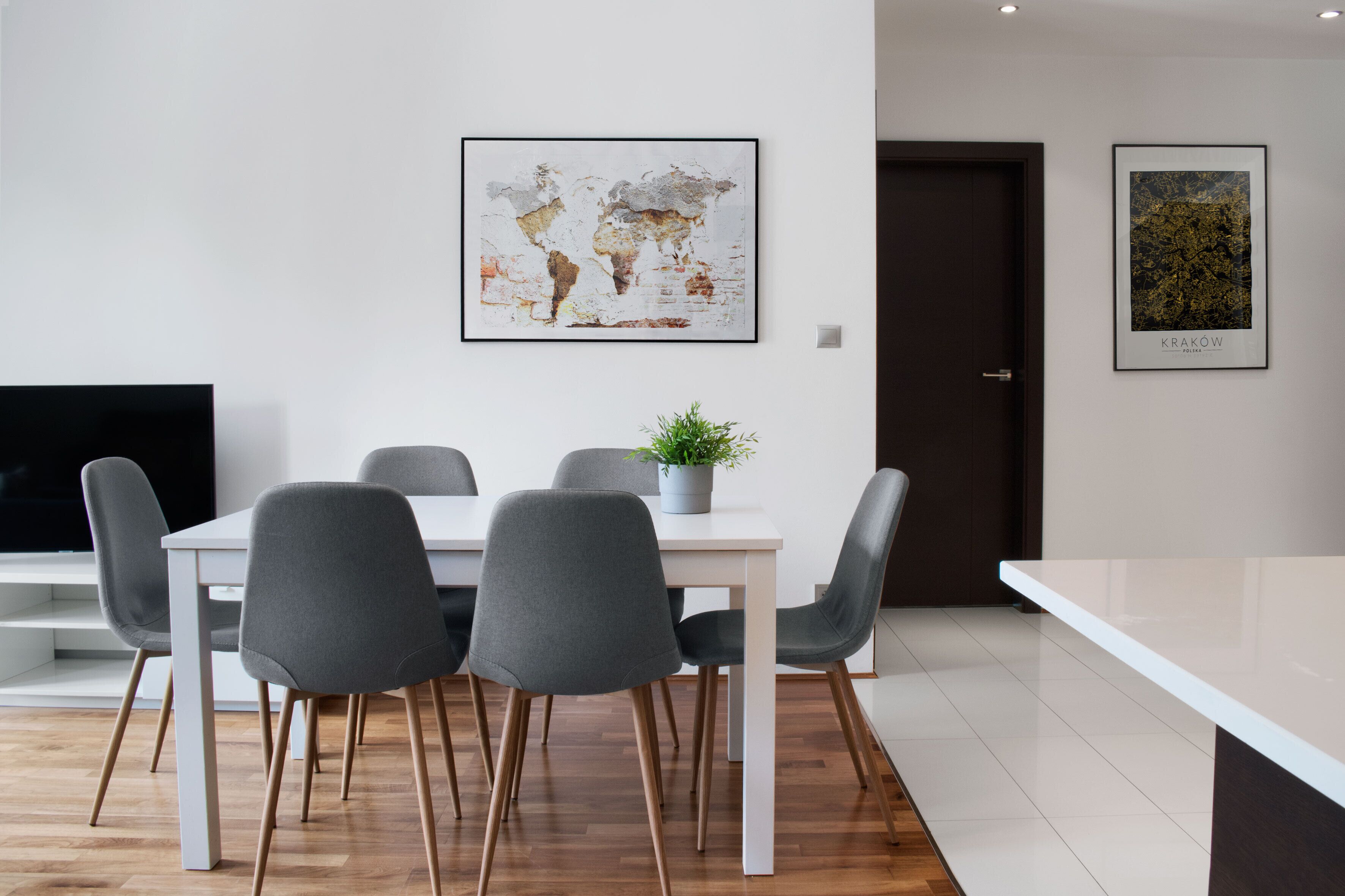 Un comedor moderno con una mesa blanca, sillas grises y una planta en maceta.