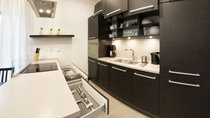 A modern kitchen with dark cabinets, a stainless steel sink, and a built-in oven.
