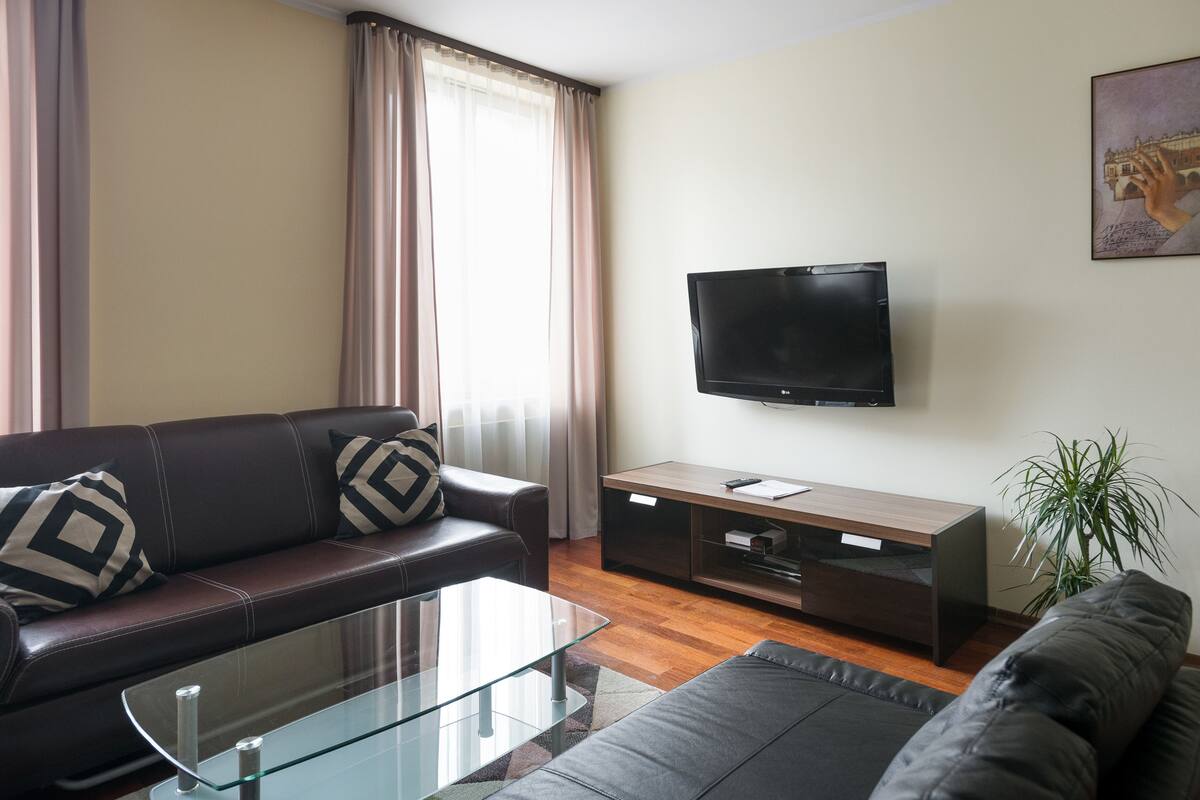 Ein modernes Wohnzimmer mit einer Ledersofa, einem Glastisch, einem an der Wand montierten Flachbildfernseher und einer Holz-Unterhaltungseinrichtung.