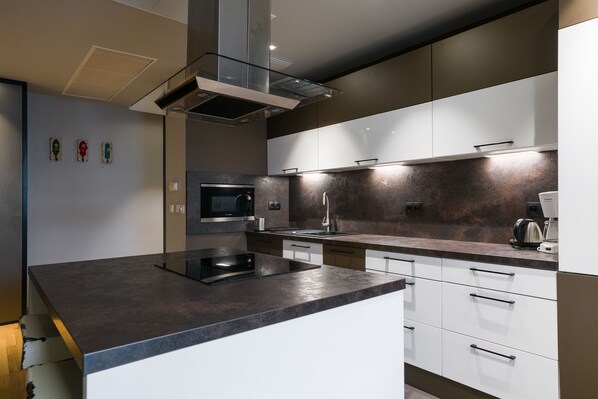 Una cocina moderna con una isla central, microondas integrado y electrodomésticos de acero inoxidable.
