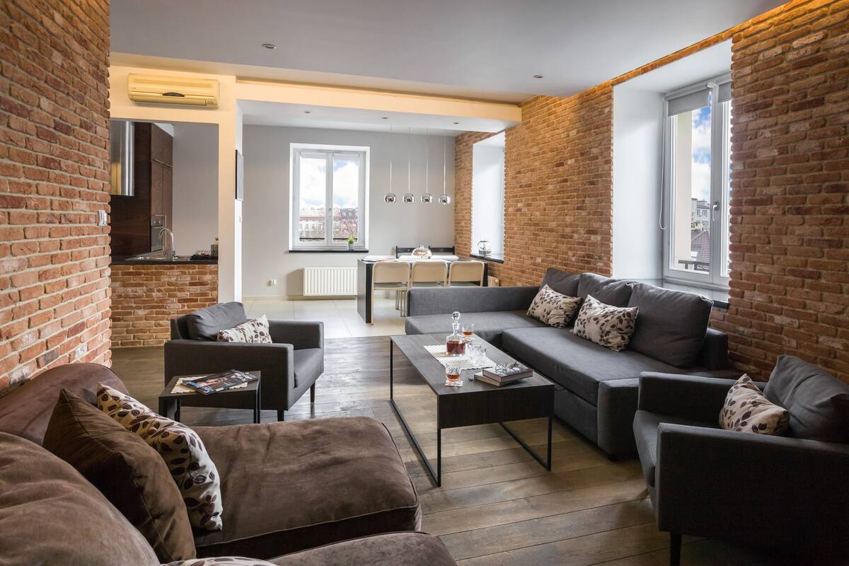 Ein modernes Wohnzimmer mit einer Sofagarnitur, einem Couchtisch und einem Essbereich mit Tisch und Stühlen.