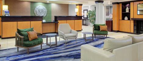 A hotel lobby with a reception desk, seating area, and a fireplace.