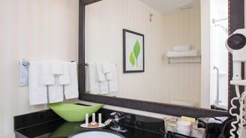 A bathroom with a black countertop, a green basin, a large mirror, and a towel rack.