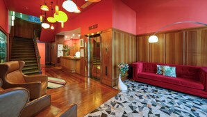 A lobby with a red sofa, wooden flooring, and a staircase.