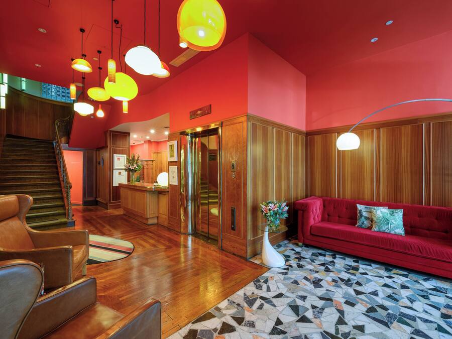 Un hall d’entrée avec un canapé rouge, un plancher en bois et un escalier.