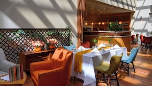 A dining area with tables set for two, featuring a mix of modern and classic chairs.