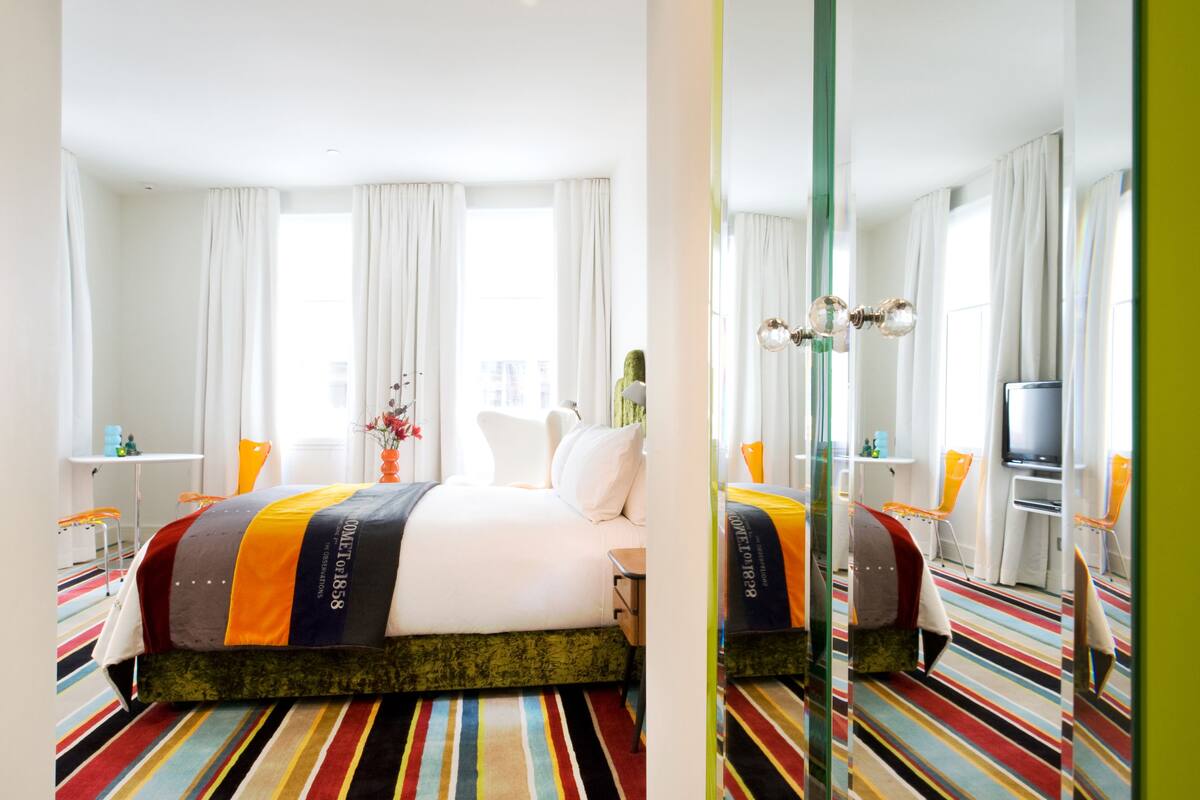 A hotel room with a bed, a TV, a desk, and a chair.