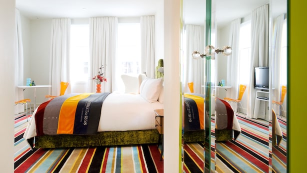 A hotel room with a bed, a TV, a desk, and a chair.