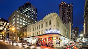 A hotel with a classic facade, a marquee sign, and a street view with cars and buildings.