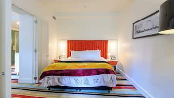 A hotel room with a bed, bedside lamps, a framed picture on the wall, and a striped carpet.