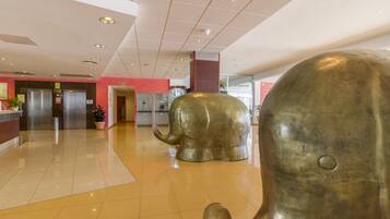 Un vestíbulo con piso brillante, una recepción y una gran escultura de elefante.