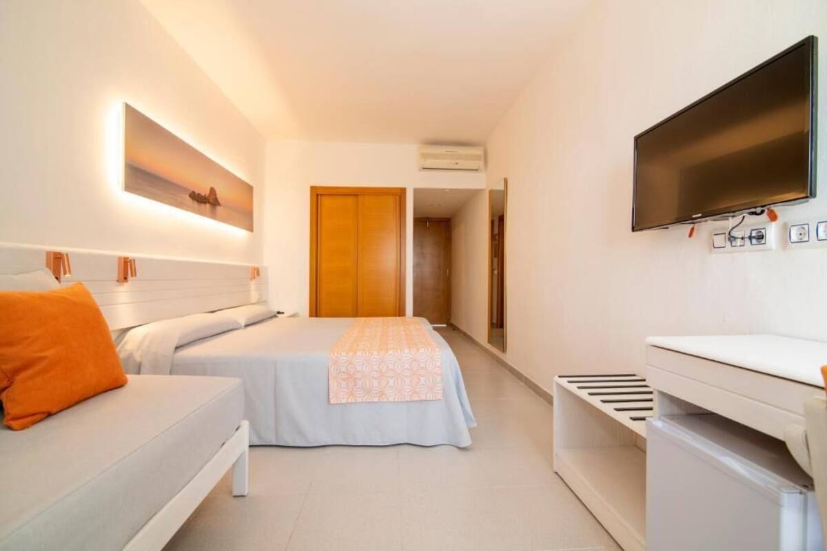 Une chambre d’hôtel équipée d’un lit, d’une table de chevet, d’un téléviseur et d’un climatiseur fixé au mur.