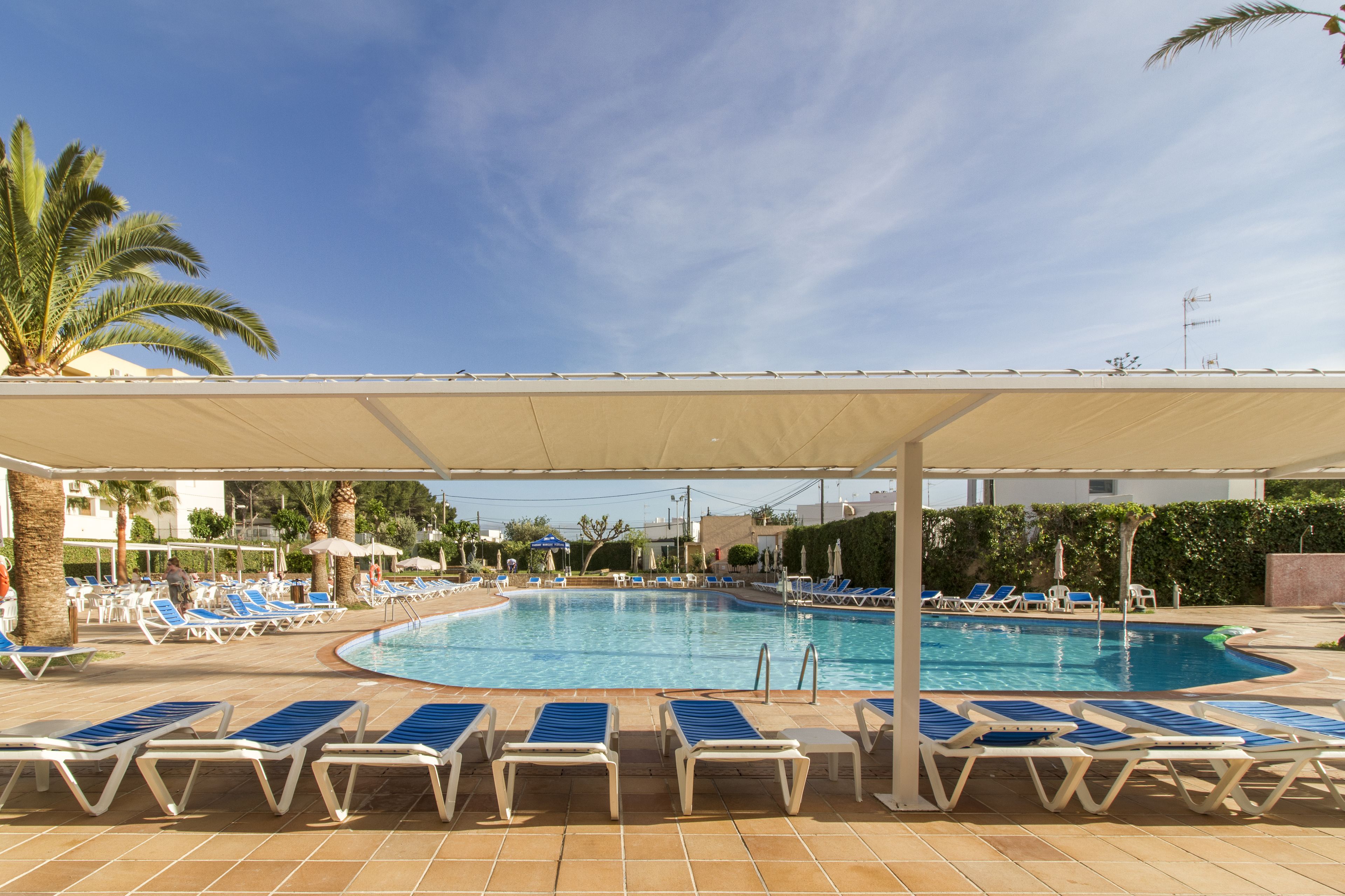 A pool area with sun loungers and a covered seating area.