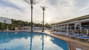 A swimming pool with lounge chairs and palm trees.