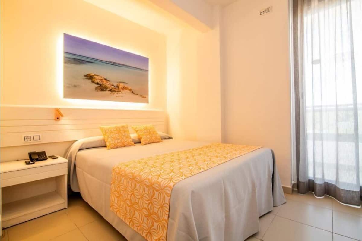 Une chambre d’hôtel avec un lit, une table de chevet et un tableau au mur.