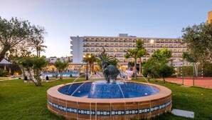 Een binnenplaats met een fontein, een beeld en een hotel op de achtergrond.