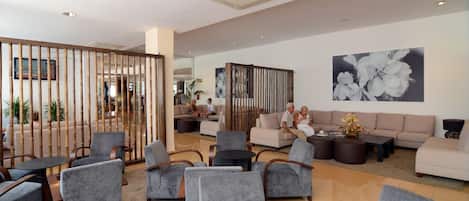 A modern lounge area with grey upholstered chairs, a large sofa, and a decorative bamboo screen.