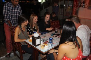 A group of people seated around a table with a board game, a can of beer, and a plate of food. - Big Apple Hotel (Istanbul)