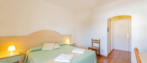 Een slaapkamer met een bed, nachtlampjes, een stoel en een deur.