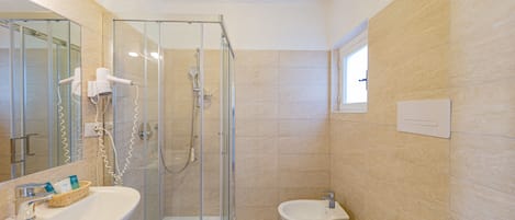 Une salle de bain moderne avec une douche à parois de verre, un lavabo avec un miroir et un bidet.