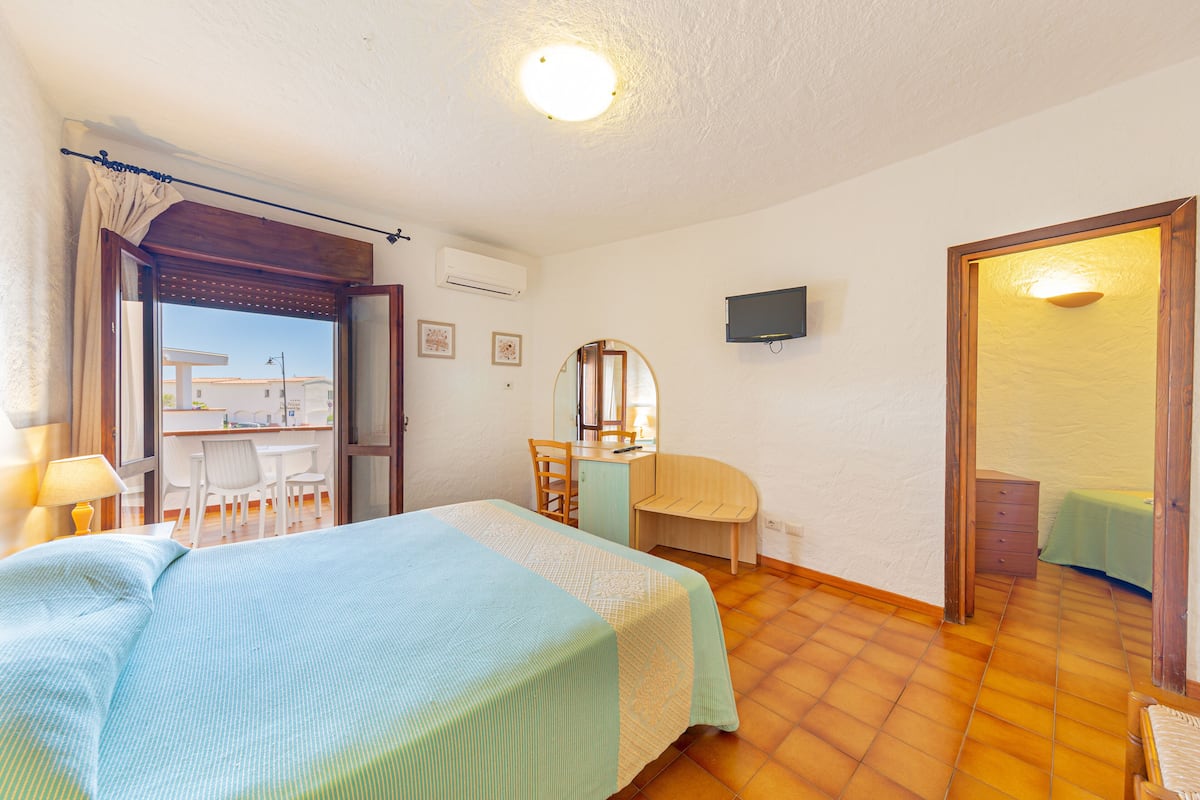 Ein Schlafzimmer mit Bett, Schreibtisch, Stuhl und Fernseher an der Wand.