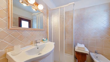 A bathroom with a large sink, a mirror, a shower, and a bidet.