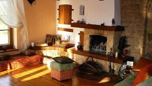 Un salon chaleureux avec une cheminée, un plancher en bois et un mur en pierre.