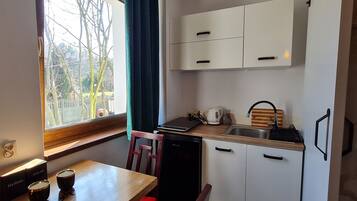 A compact kitchen with a window, a sink, a refrigerator, and a dining area with a table and chairs.