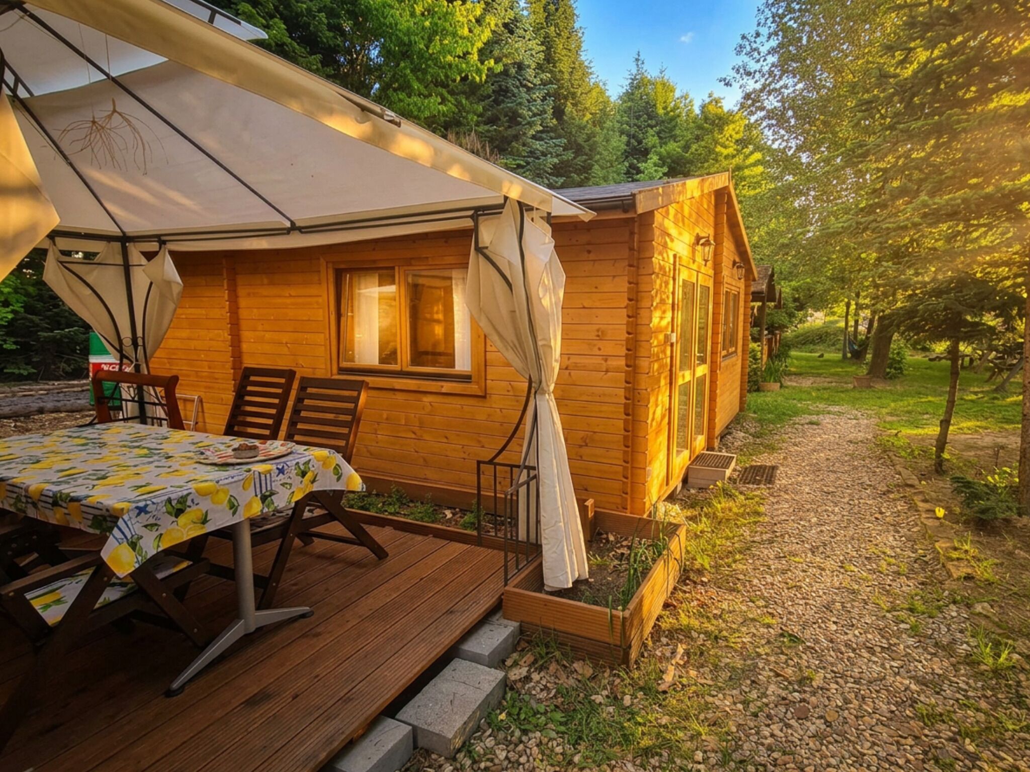 A wooden cabin with a table and chairs, a covered patio, and a garden path.