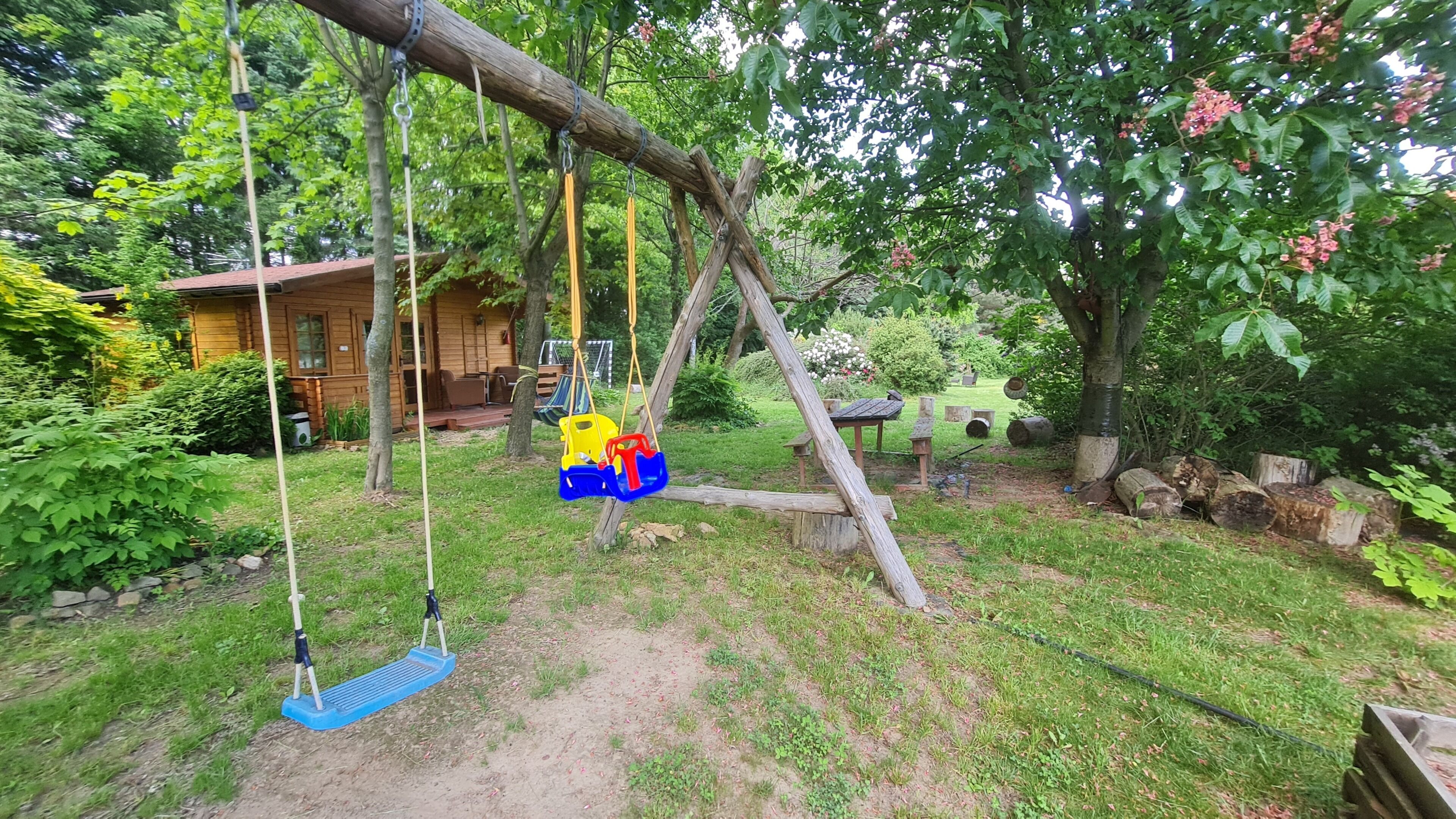 A wooden swing set in a garden with a house in the background.