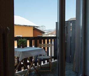 Eine Terrasse mit Tisch und Stühlen, einem Blumentopf und Blick auf ein Gebäude mit verschneitem Dach.