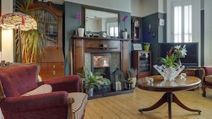 A living room with a fireplace, a round table, and a large mirror. - Avoca House (Dublin)
