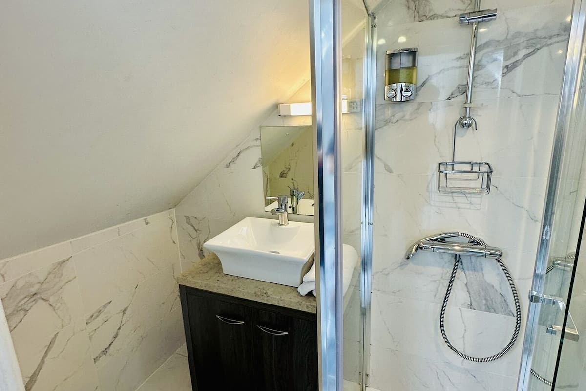 A modern bathroom with a glass-enclosed shower, a white sink, and a dark-toned vanity.