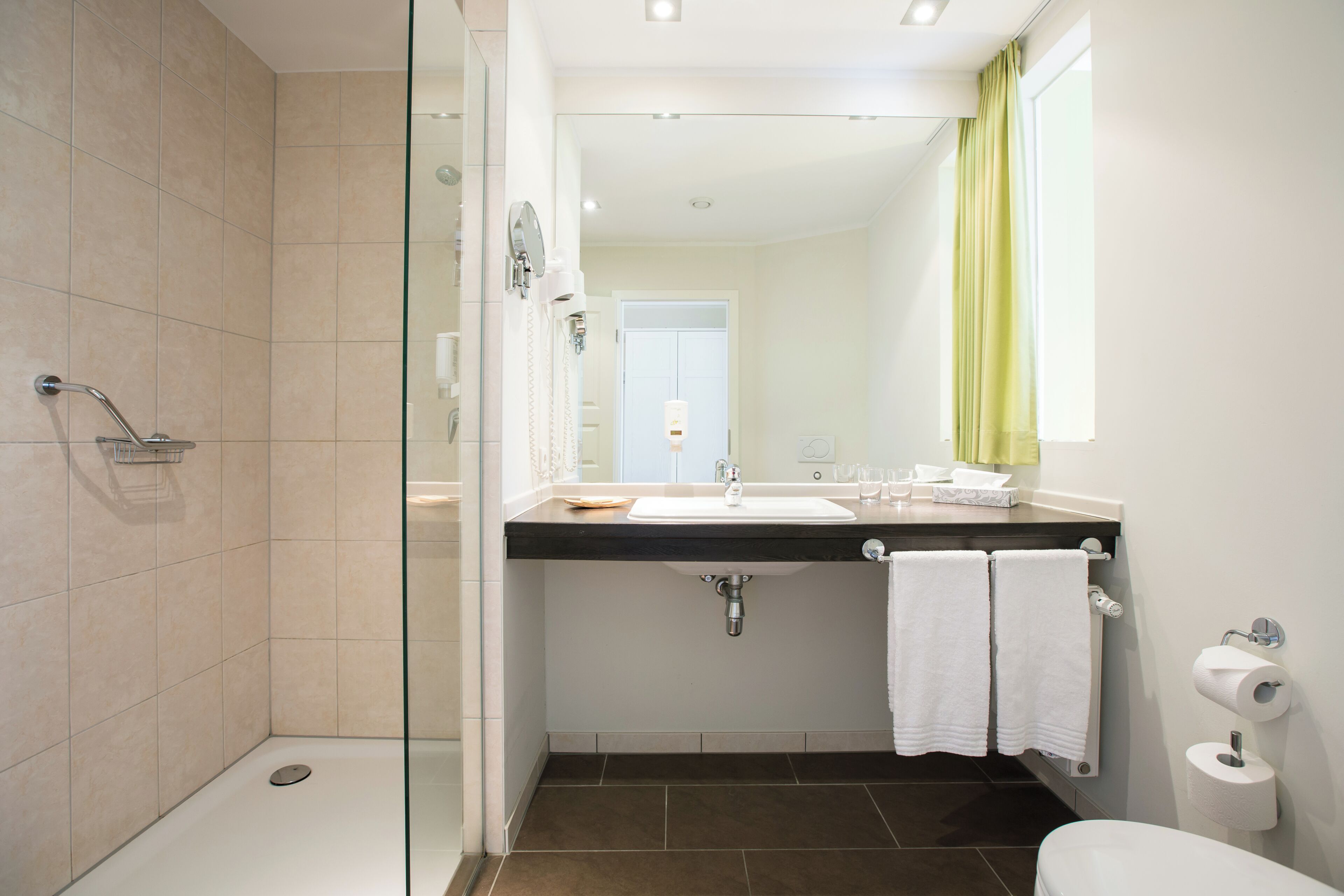 Une salle de bain moderne avec une douche à parois de verre, un lavabo avec un miroir et des toilettes.